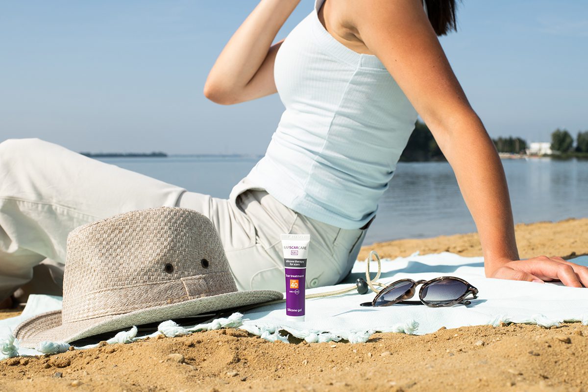 Bapscare SPF silicone scar treatment tube in front of woman at the beach